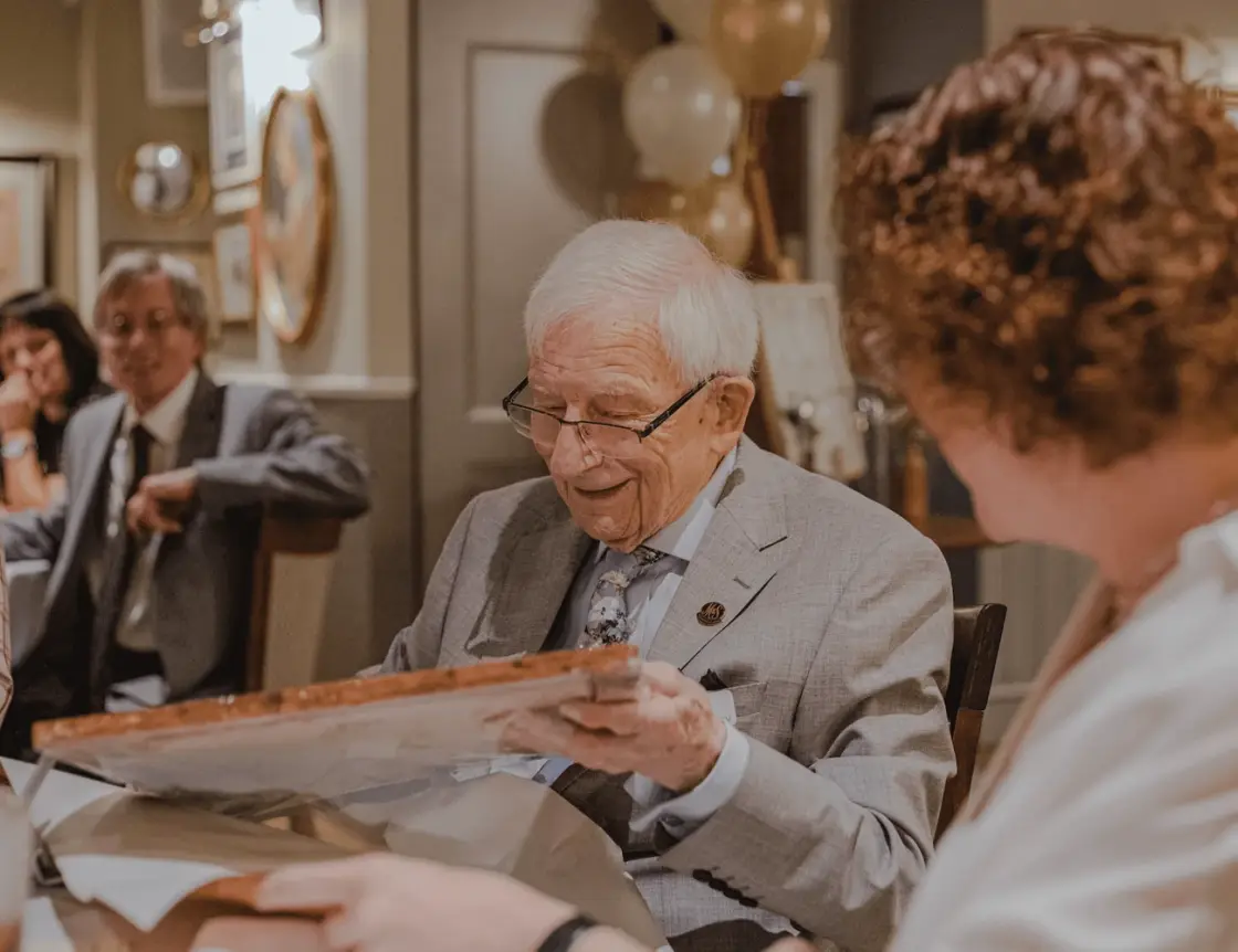 An older man at a table, reading a piece of paper