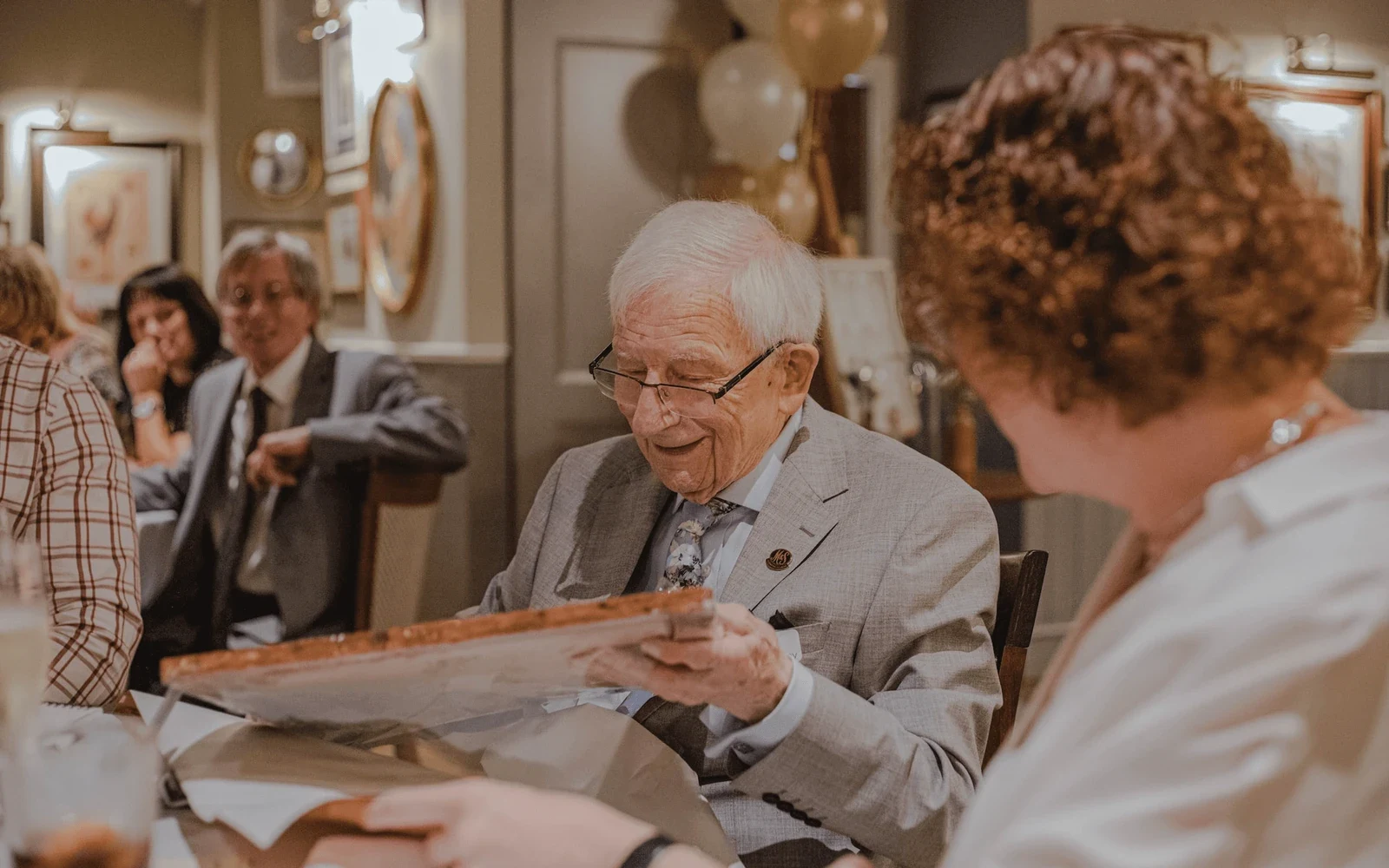 An older man at a table, reading a piece of paper