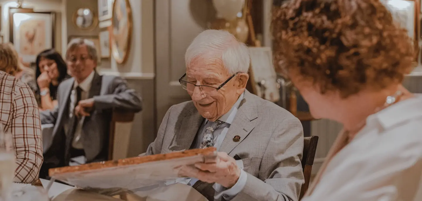 An older man at a table, reading a piece of paper